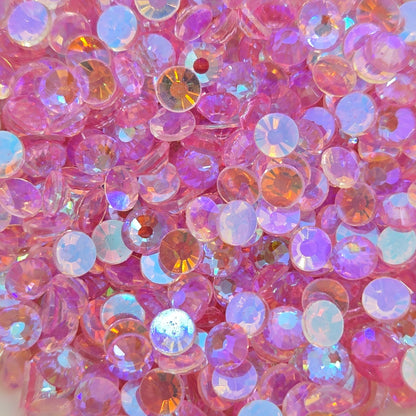 A dish filled with light pink, flat-backed rhinestones with a shiny, reflective surface.