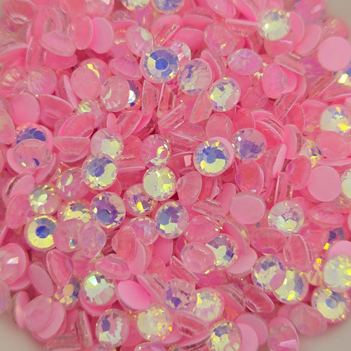 A collection of pink luminous opal flat back rhinestones in a white dish, with a blurred background.