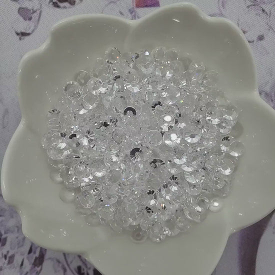 Transparent Clear Unfoiled rhinestones in a glass bowl slowly spinning and sparkling