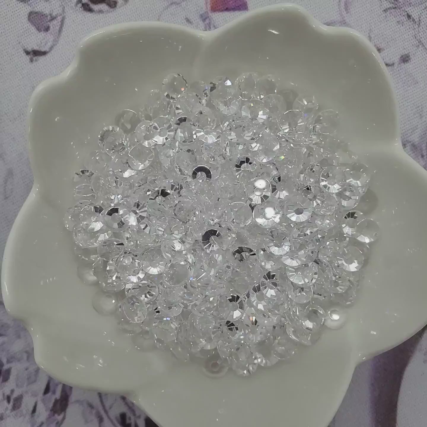 Transparent Clear Unfoiled rhinestones in a glass bowl slowly spinning and sparkling