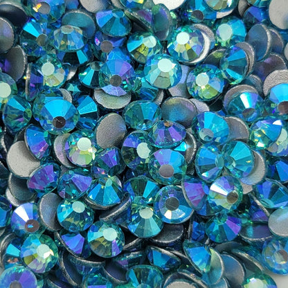 A bowl of blue and aqua colored glass rhinestones with a shimmering, iridescent finish.