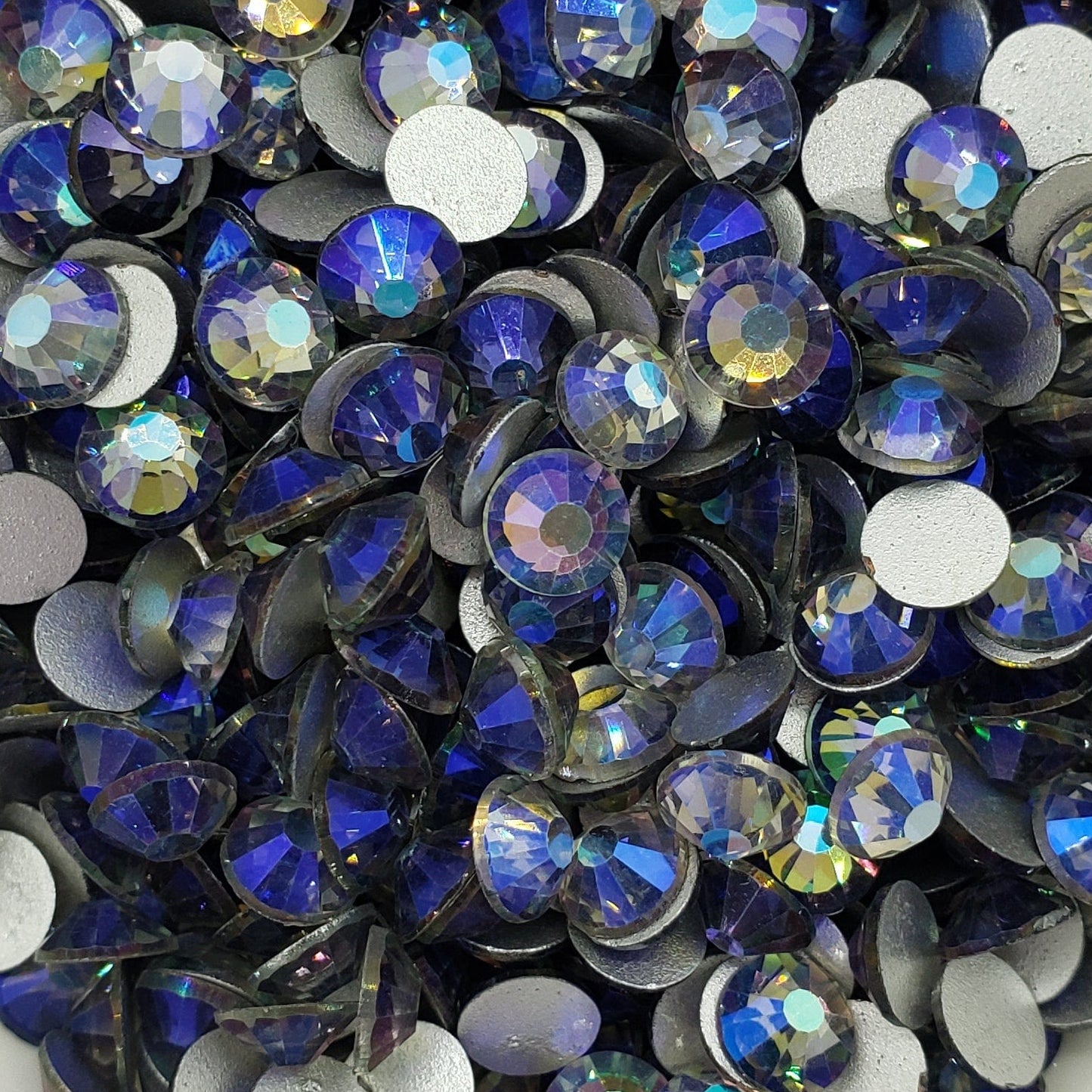 A collection of black diamond shaped rhinestones with a sparkling effect, displayed in a white dish.