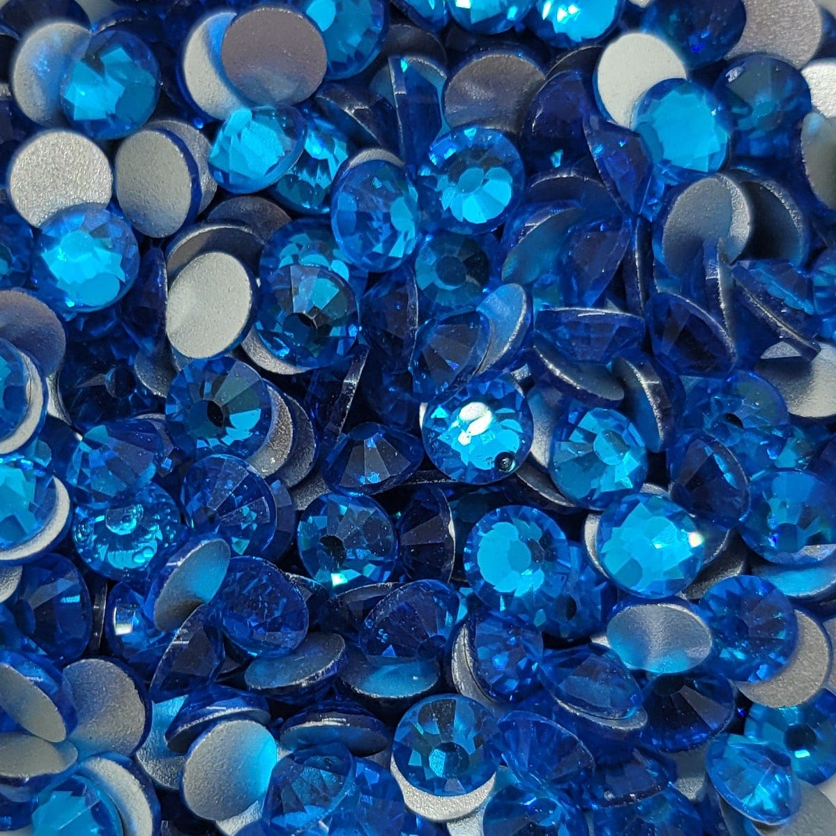 A bowl of blue KiraKira glass rhinestones by CrystalNinja, showcasing their shiny and sparkling appearance.