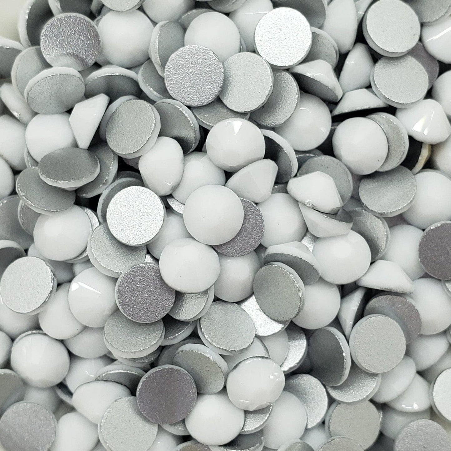 A bowl full of flatback solid white rhinestones intended for crafting and decoration.