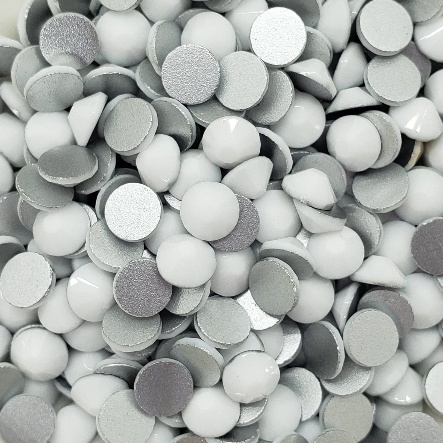 A bowl full of flatback solid white rhinestones intended for crafting and decoration.
