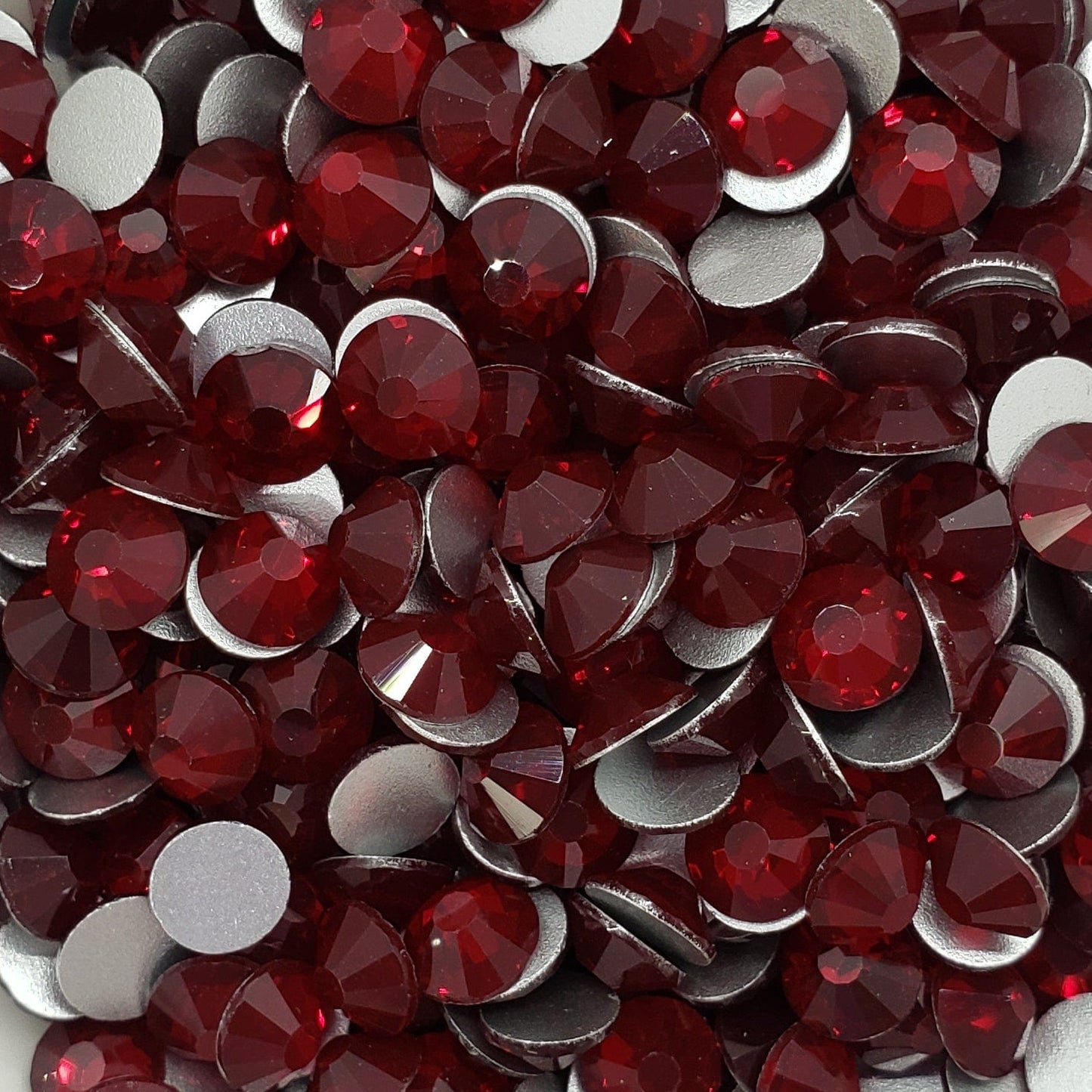 A dish containing red glass rhinestones with a white flower-like shape on a white surface.