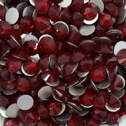 A dish containing red glass rhinestones with a white flower-like shape on a white surface.