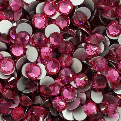 A dish containing pink glass rhinestones with a sparkle effect, intended for crafting and decoration.