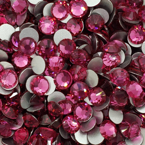 A dish containing pink glass rhinestones with a sparkle effect, intended for crafting and decoration.