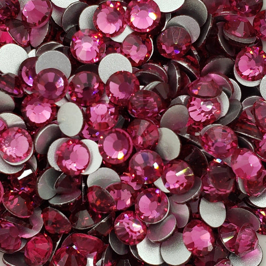 A dish containing pink glass rhinestones with a sparkle effect, intended for crafting and decoration.