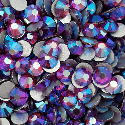 A collection of fuchsia-colored glass rhinestones scattered on a white surface.