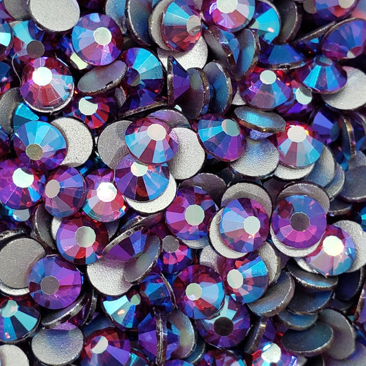 A collection of fuchsia-colored glass rhinestones scattered on a white surface.