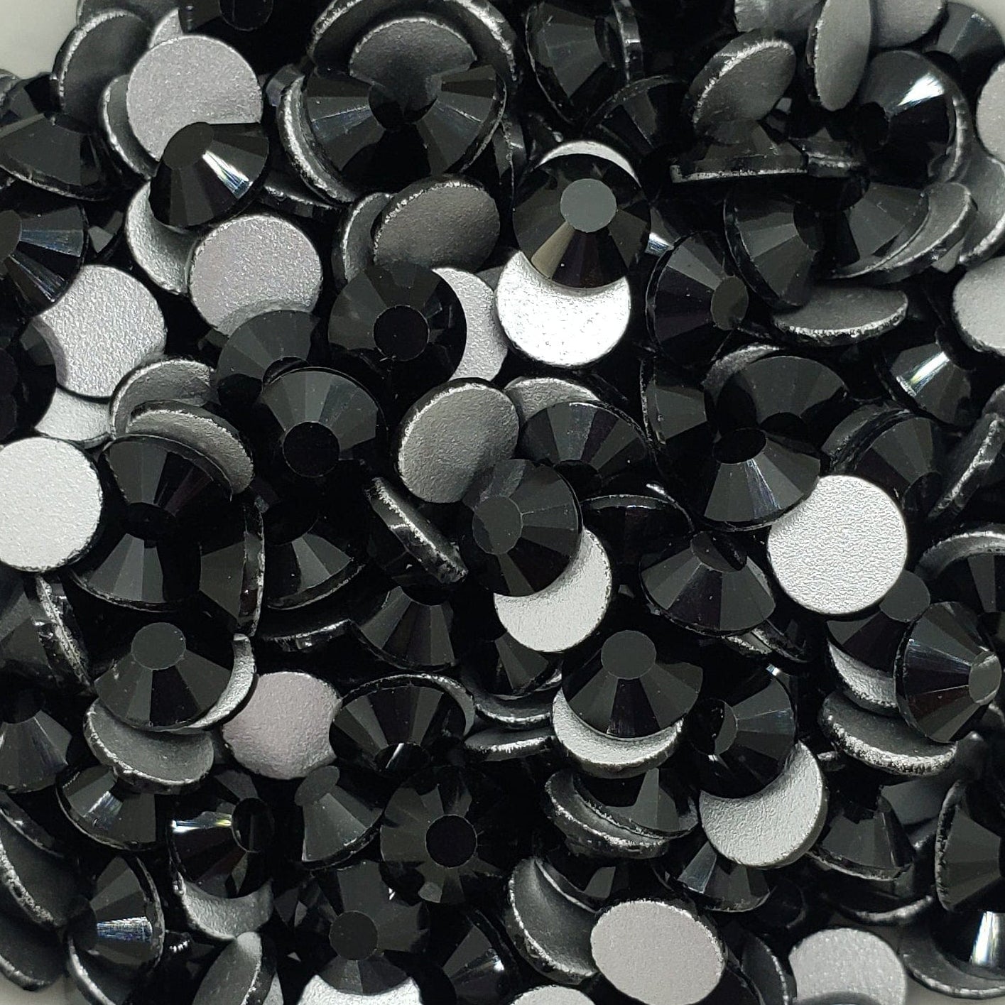 A bowl filled with black flatback glass rhinestones.