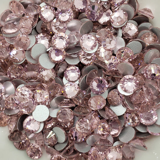 A dish containing pink glass rhinestones with a shiny surface.