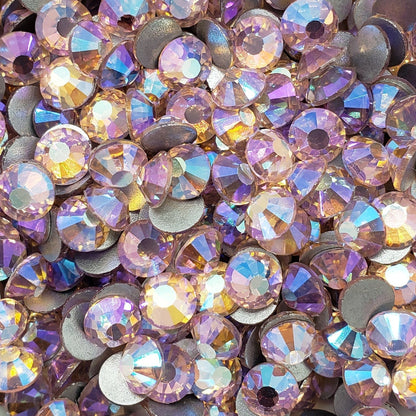 A bowl filled with light rose colored glass rhinestones with an aurora borealis effect.