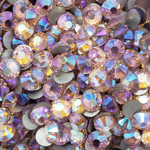 A bowl filled with light rose colored glass rhinestones with an aurora borealis effect.