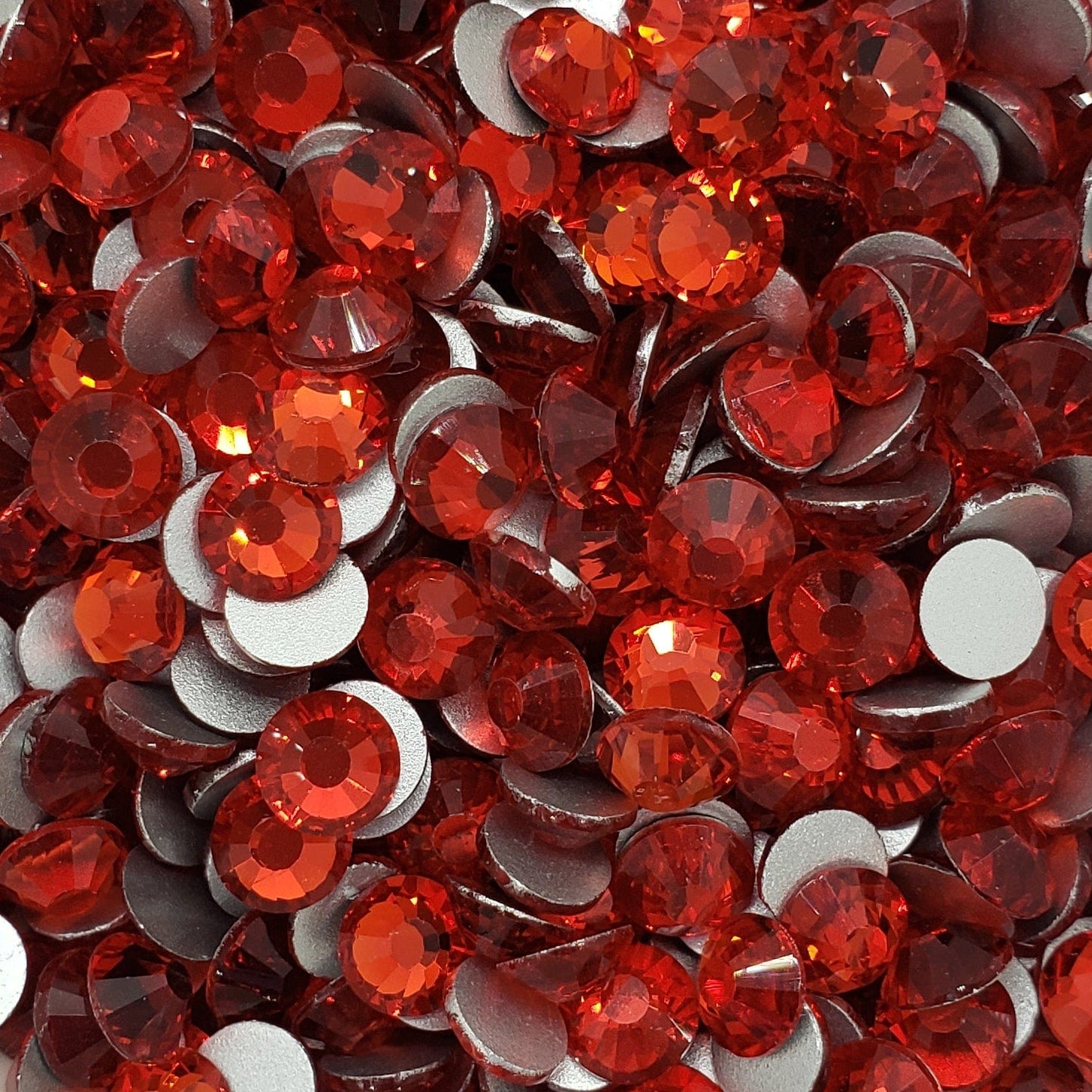 A bowl of red glass rhinestones with a shiny, reflective surface.
