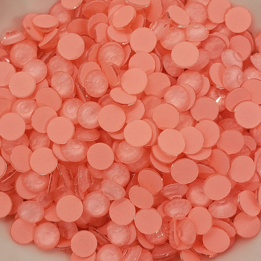 A bowl filled with round, orange-colored glass rhinestones.