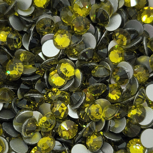 A bowl filled with yellow and clear round rhinestones on a floral patterned background.
