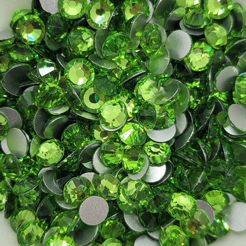 A bowl filled with green glass rhinestones on a table.