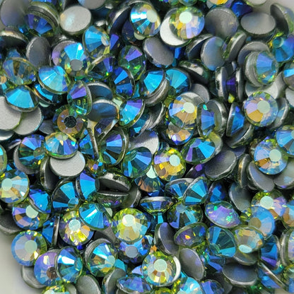 A white bowl filled with multicolored kirakira glass rhinestones, with a blurred pink background.