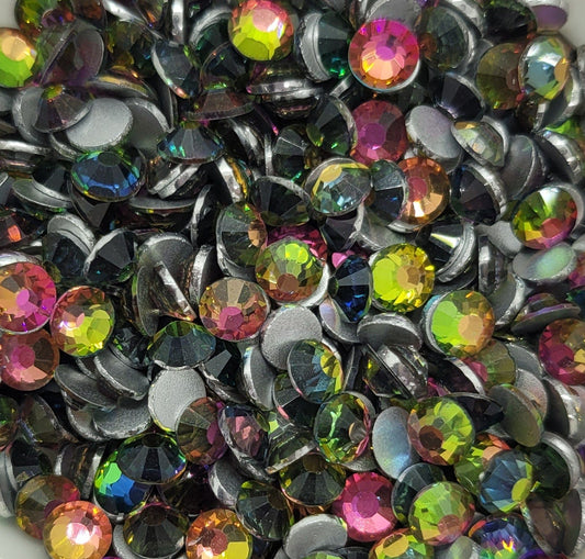 A bowl of multicolored round glass rhinestones with a shiny, reflective surface.