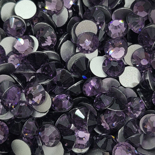 A dish filled with purple glass rhinestones, intended for use in crafting and jewelry making.