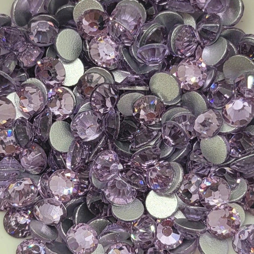 A bowl filled with purple glass rhinestones on a patterned background.