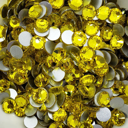 A bowl filled with yellow flatback glass rhinestones.