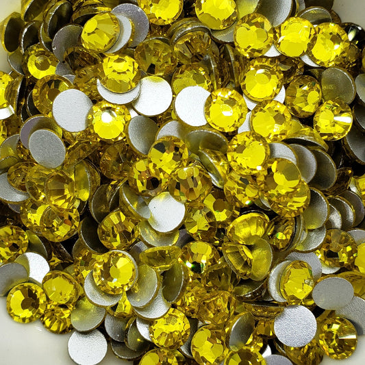 A bowl filled with yellow flatback glass rhinestones.