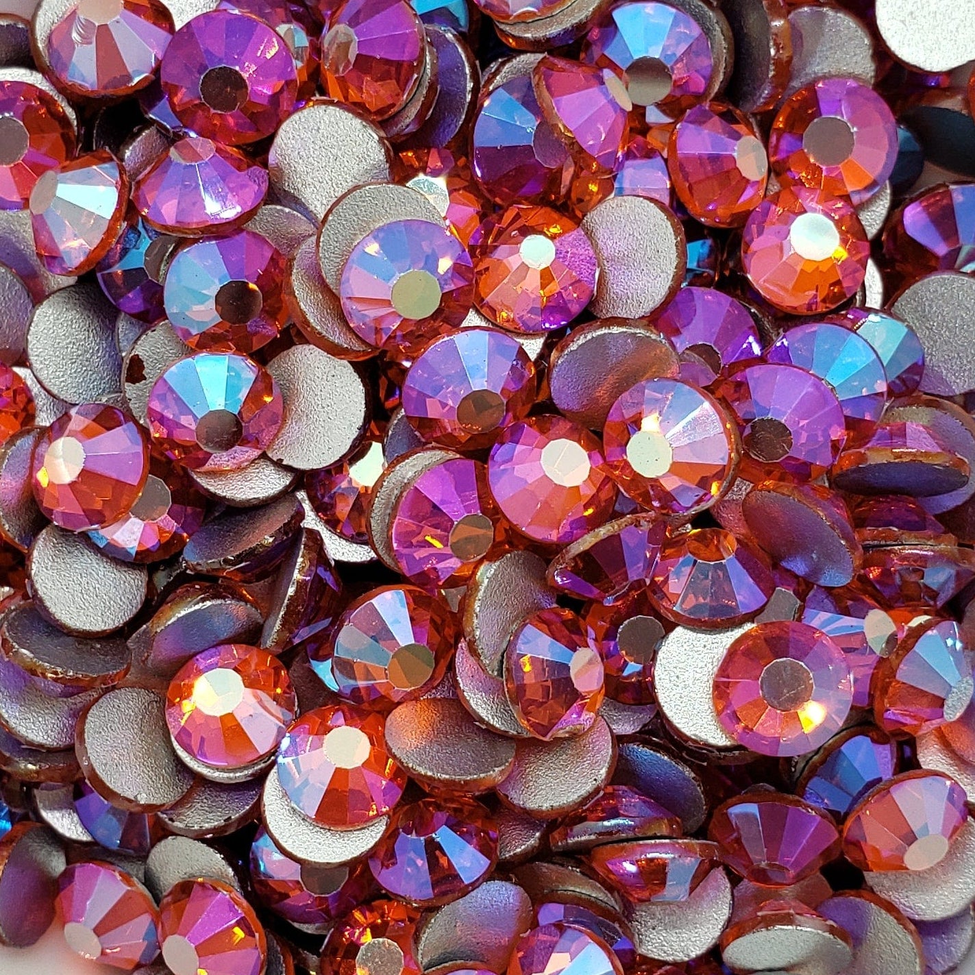A bowl filled with multicolored flatback rhinestones with a aurora borealis effect.